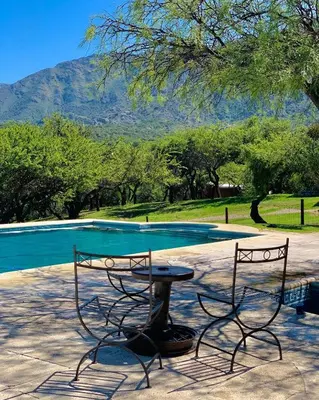 two chairs and a table in front of a pool at Cabañas San Miguel in Cortaderas