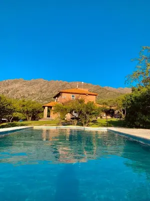 a pool of blue water in front of a house at Cabañas San Miguel in Cortaderas