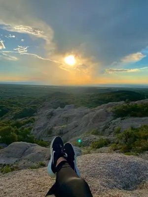 a person sitting on top of a mountain looking at the sunset at Cabañas San Miguel in Cortaderas