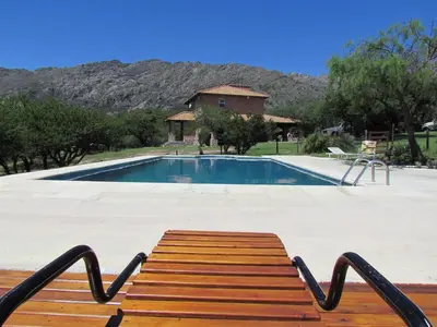 a wooden bench sitting in front of a swimming pool at Cabañas San Miguel in Cortaderas