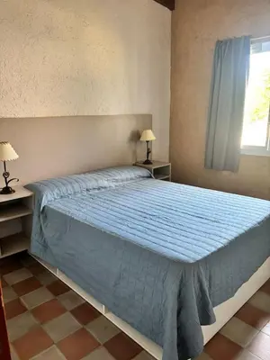 a bedroom with a bed with a blue comforter and a window at Cabañas Dos Soles in Cordoba