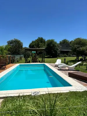 a swimming pool with two chairs and a gazebo at Cabañas Dos Soles in Cordoba