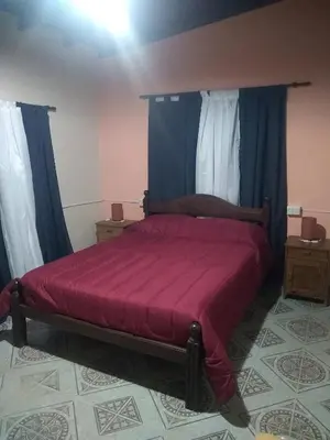 a bedroom with a red bed with blue curtains at Departamento NataFeli in Santa Rosa de Calamuchita