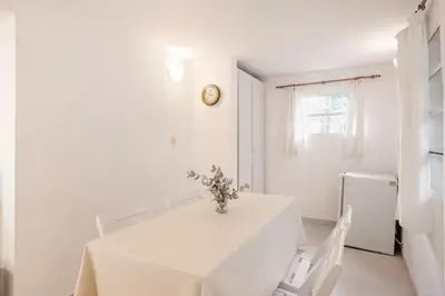 a white kitchen with a white table and a white refrigerator at Hermosa Casa V. General Belgrano in Villa General Belgrano