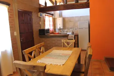 a kitchen with a wooden table with chairs and a refrigerator at Cabañas Las Marias 1 in Cordoba