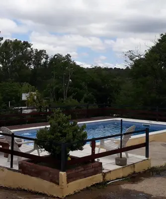 a swimming pool with a tree in a planter next to a fence at Cabañas Las Marias 1 in Cordoba