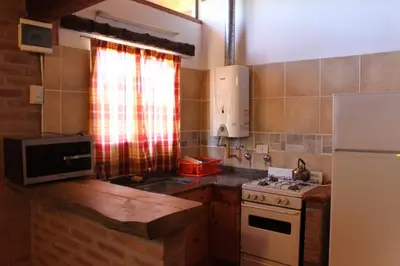 a kitchen with a stove and a white refrigerator at Cabañas Las Marias 1 in Cordoba