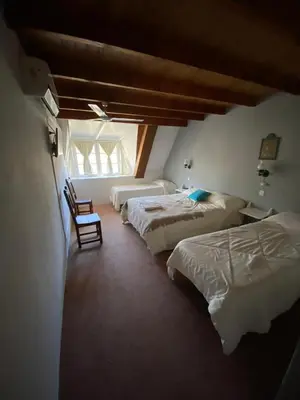 a bedroom with three beds and a chair in it at Hotel Prater in Villa General Belgrano