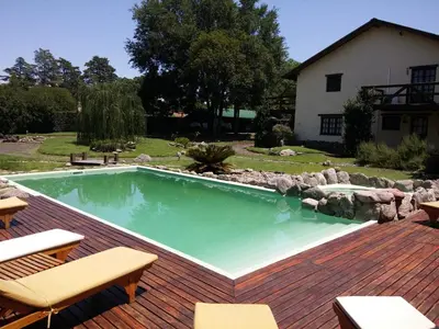 a swimming pool on a deck with chairs and a house at la matilda in Santa Rosa de Calamuchita