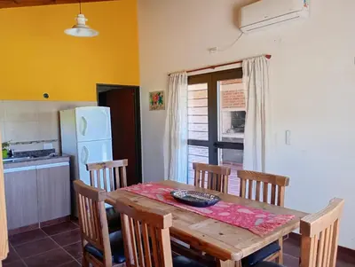 a kitchen with a wooden table with chairs and a refrigerator at Casa Erica in Santa Rosa de Calamuchita