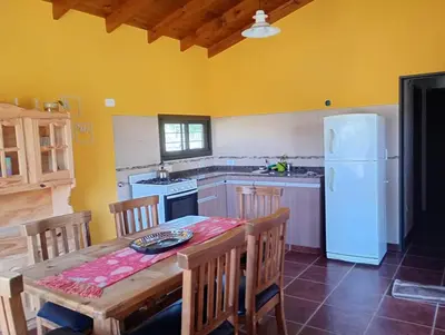 a kitchen with a table and a white refrigerator at Casa Erica in Santa Rosa de Calamuchita