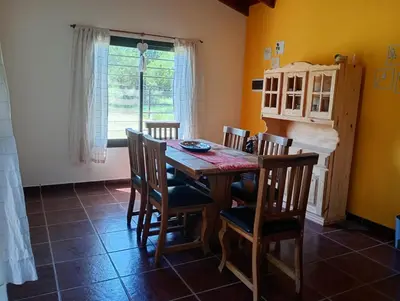 a dining room with a wooden table and chairs at Casa Erica in Santa Rosa de Calamuchita