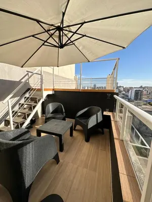 a patio with chairs and an umbrella on a balcony at Departamento c/ piscina climatizada privada, 4 habitaciones en el centro de Cordoba in Cordoba