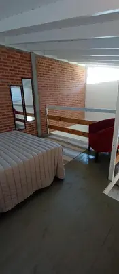 a bedroom with a bed and a bench and a brick wall at Schönes Loft in Villa General Belgrano