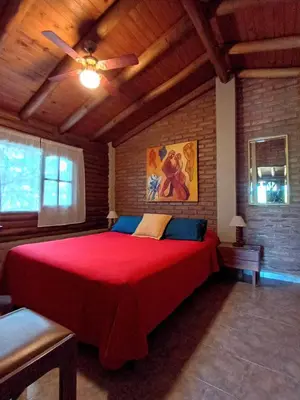 a bedroom with a large red bed with a ceiling at Cabaña de troncos en Nono, Córdoba in Nono