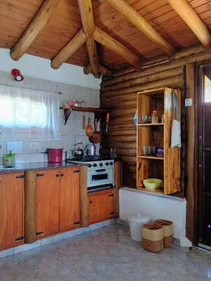 a kitchen with wooden cabinets and a stove at Cabaña de troncos en Nono, Córdoba in Nono