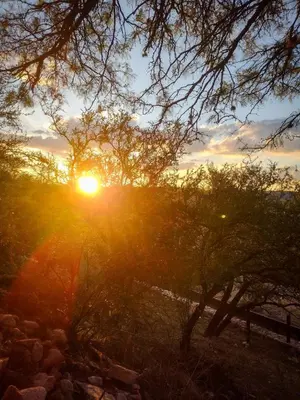 a sunset with the sun setting behind some trees at Cabaña de troncos en Nono, Córdoba in Nono