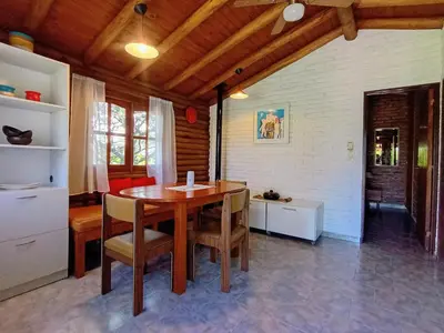 a dining room with a wooden table and chairs at Cabaña de troncos en Nono, Córdoba in Nono