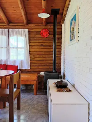 a kitchen with a stove and a dining room with a table at Cabaña de troncos en Nono, Córdoba in Nono