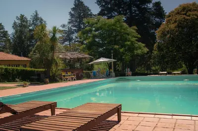 a swimming pool with two benches in a yard at Hotel Lago Los Molinos in Villa Ciudad de America