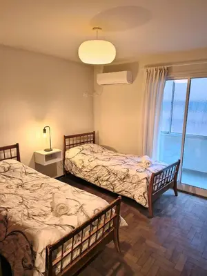 two beds in a room with a large window at HERMOSO - CATEGORIA Departamento 90 m2 CENTRO con COCHERA opcional in Cordoba