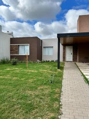 a house with a grass yard next to a building at Reserva Tajamar in Alta Gracia