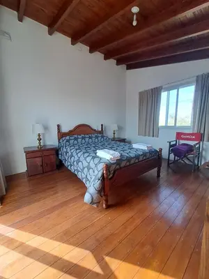 a bedroom with a bed and a wooden floor at La Casita Estanciera in Estancia Vieja