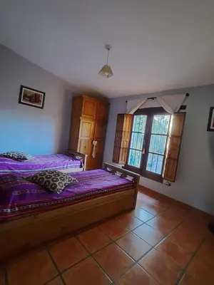 a bedroom with a bed with purple sheets and windows at Casa en Sierras de Córdoba, Villa la Bolsa. in La Bolsa