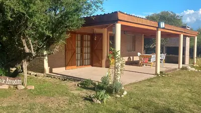 a small cabin with a porch and a table and chairs at Cabaña Rincón de Afrodita in San Lorenzo