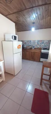a kitchen with a white refrigerator and wooden cabinets at Cabaña Rincón de Afrodita in San Lorenzo