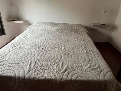 a bed in a bedroom with a white bedspread at Chalet Mariam in Villa Carlos Paz