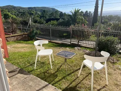 three white chairs and a table in the grass at Chalet Mariam in Villa Carlos Paz