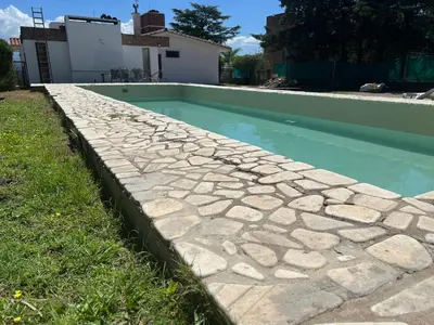 a swimming pool with a stone path around it at Chalet Mariam in Villa Carlos Paz
