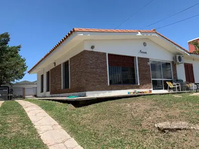 a brick house with a lawn in front of it at Chalet Mariam in Villa Carlos Paz