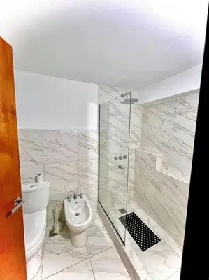 a bathroom with a shower and a toilet and a sink at Hospedaje Frente al Rio Dos Soles in Santa Rosa de Calamuchita