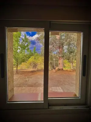 a window with a view of a park through it at Hospedaje Frente al Rio Dos Soles in Santa Rosa de Calamuchita