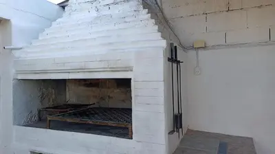 a white brick fireplace with a wooden bench in it at Chalet MAX in Bialet Massé