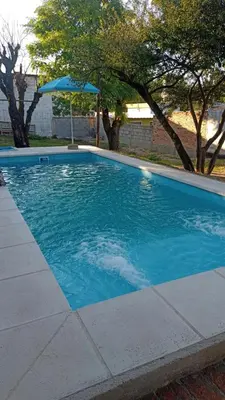 a large blue swimming pool with an umbrella at Chalet MAX in Bialet Massé