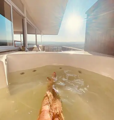 a person in a bath tub with the sun in the background at AYRES SUITE in Villa Carlos Paz