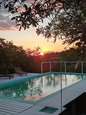 a swimming pool with a sunset in the background at Orquídeas in Quebrada de los Pozos