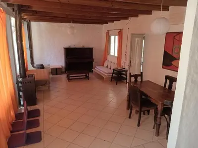a living room with a table and a piano at Orquídeas in Quebrada de los Pozos