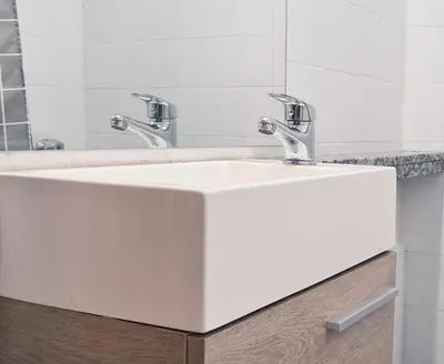 a bathroom sink with two faucets and a mirror at Casa Nómada - Centro in Cordoba