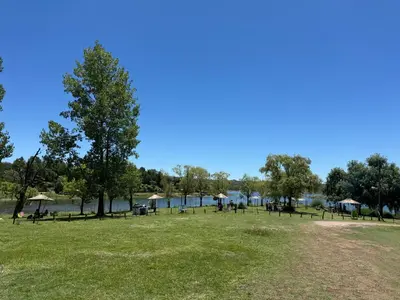 a park with a large grass field and a lake at Cabaña Clarita La Florida in La Florida