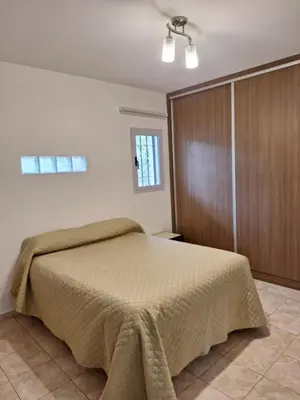 a bedroom with a bed and a wooden closet at Casa Frente Dique Piedras Moras in Almafuerte