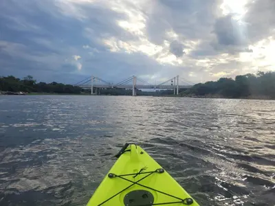 a yellow kayak on the water with a bridge in the background at Casa Frente Dique Piedras Moras in Almafuerte