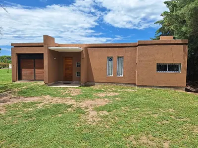 a small house on a grassy field in front at Casa Frente Dique Piedras Moras in Almafuerte