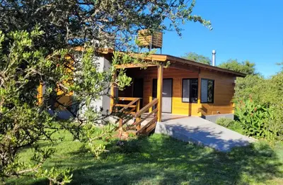 a small yellow and white house with a tree at Sueño Serrano in Santa Rosa de Calamuchita