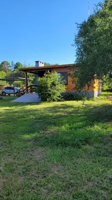a house with a grass field in front of a building at Sueño Serrano in Santa Rosa de Calamuchita