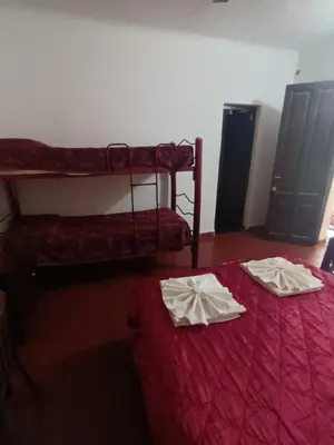 two bunk beds in a room with red sheets at Hotel Agüero in Mina Clavero