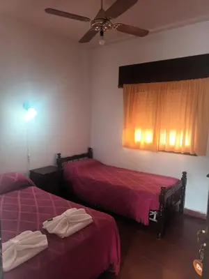 a bedroom with two beds and a ceiling fan at Hotel Agüero in Mina Clavero